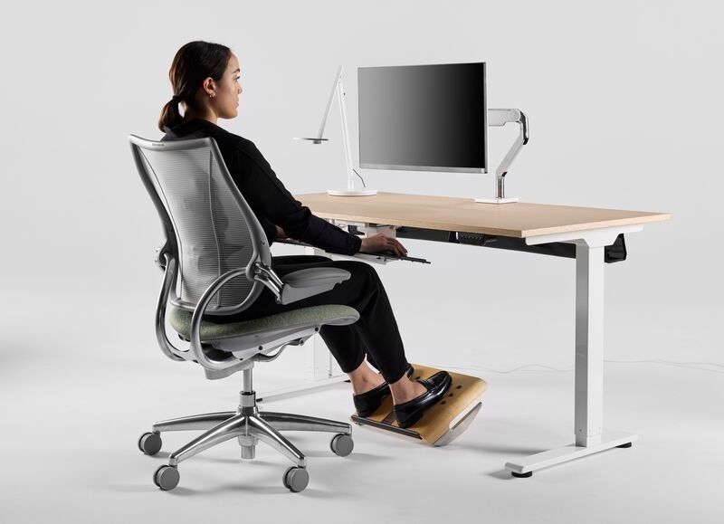 Person sitter ergonomiskt vid höj- och sänkbart skrivbord