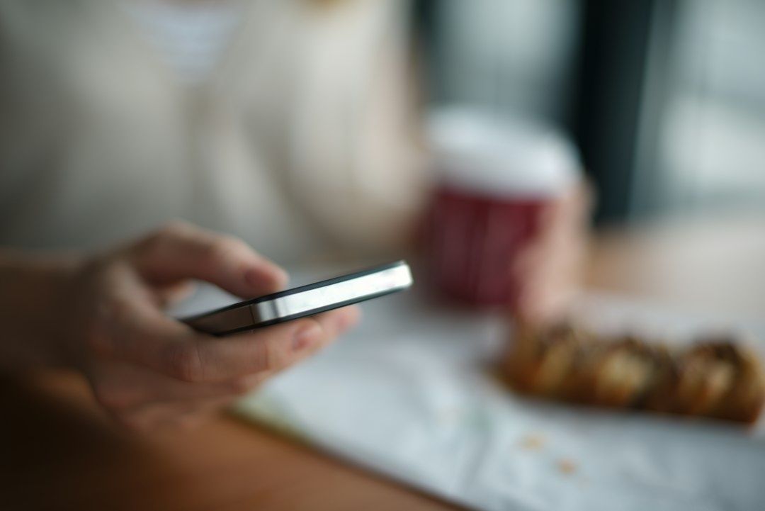 Person håller en smartphone för mobil läsning vid ett bord