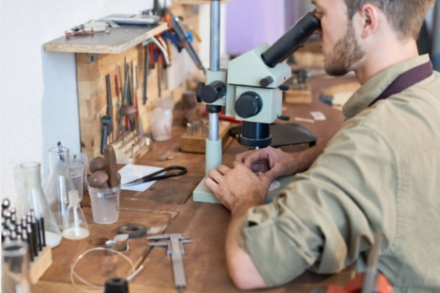 Man forskar om diamantbrev vid ett skrivbord med mikroskop och verktyg.